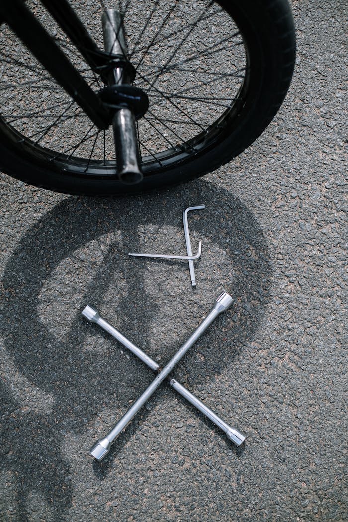 Bicycle wheel with tools on pavement, ideal for cycling maintenance themes.